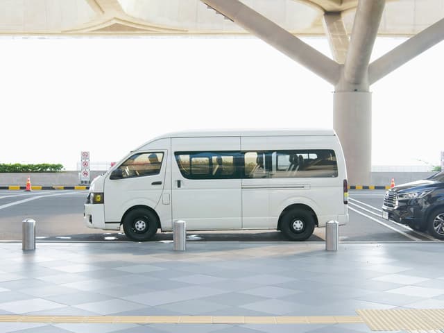 White passenger van parked at an airport terminal under a covered walkway
