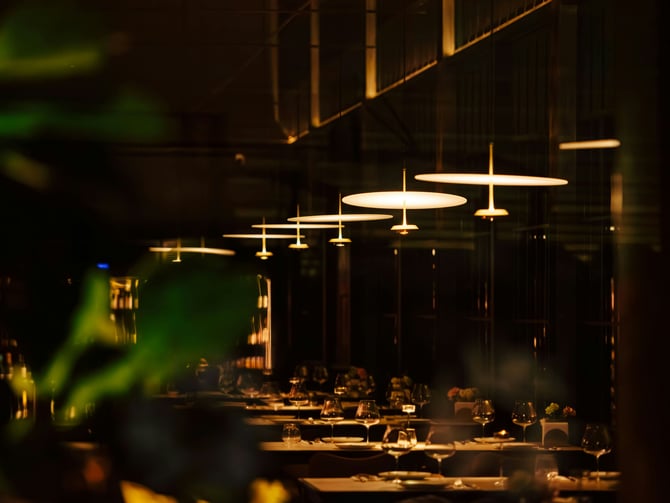 Warm restaurant interior with hanging pendant lights and set tables
