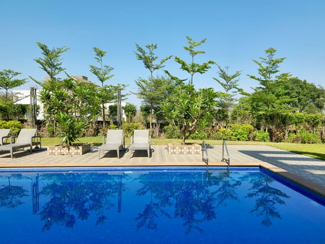 Tropical resort pool with lounge chairs and lush greenery