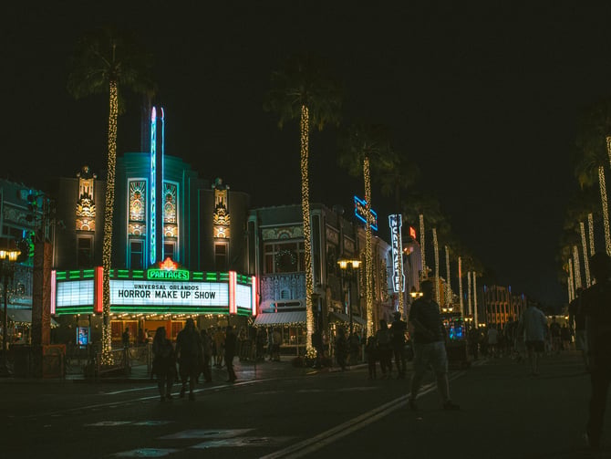Palm-lined entertainment street with neon marquee at night