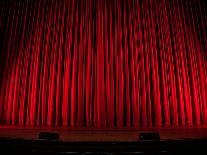 Red velvet stage curtain lit from below in a theater
