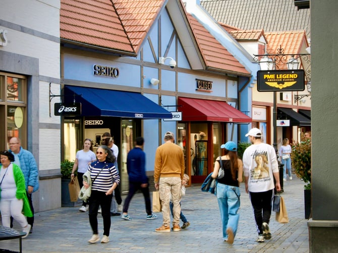 Busy outdoor shopping village with boutique storefronts