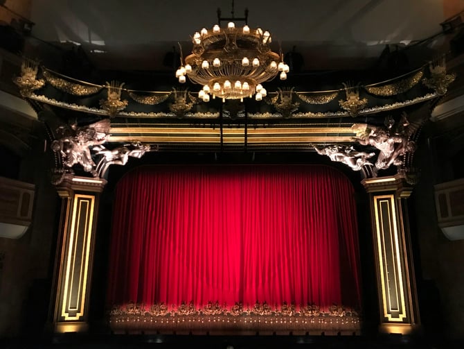 Ornate theater stage with red curtain and chandelier