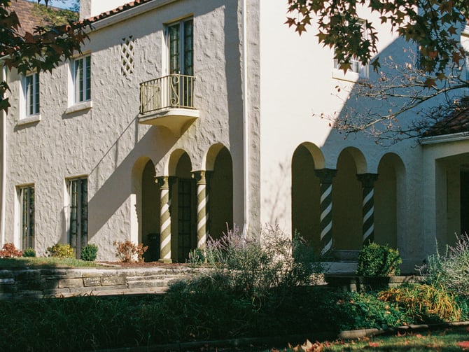 White stucco Spanish-style house with arched colonnade and garden