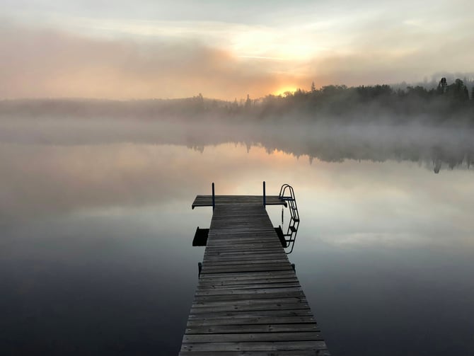 Misty lake at sunrise with a wooden dock and still water
