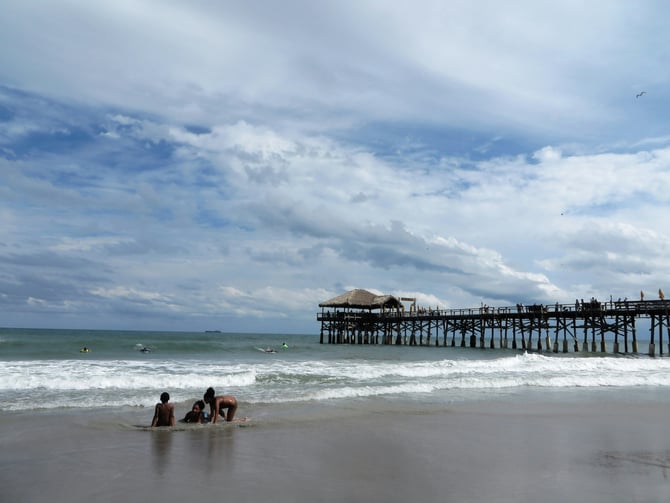 People in the surf with Cocoa Beach pier in the background