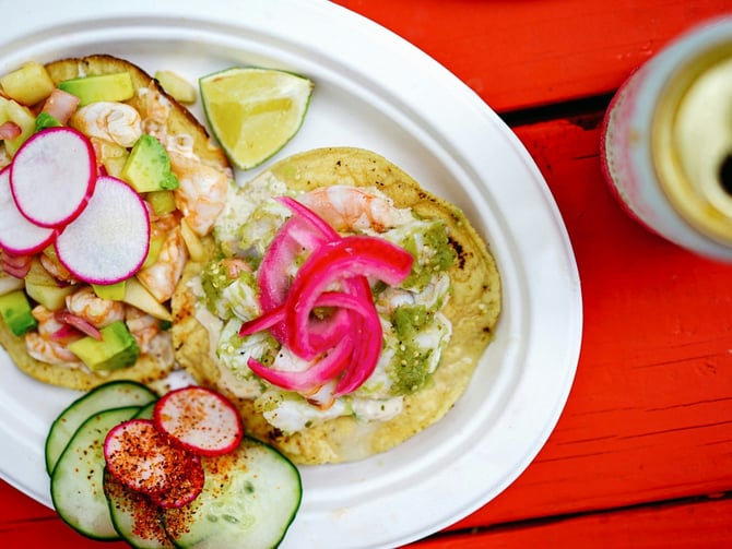 Shrimp tostada with avocado, radish and lime on a red table