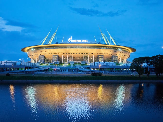 Modern stadium illuminated at dusk with water reflection