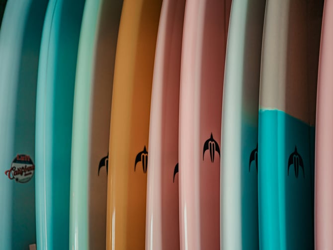 Pastel surfboards lined up in a surf shop