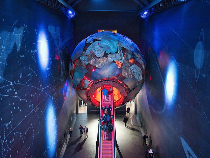 Large glowing globe inside a dramatic museum interior