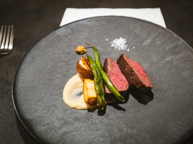 Perfectly seared steak on a dark plate with asparagus and sauce