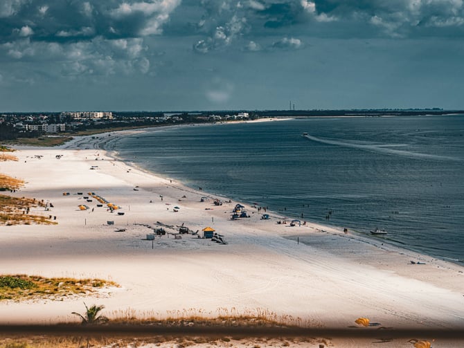 Aerial view of a long white sand beach stretching alongside the city