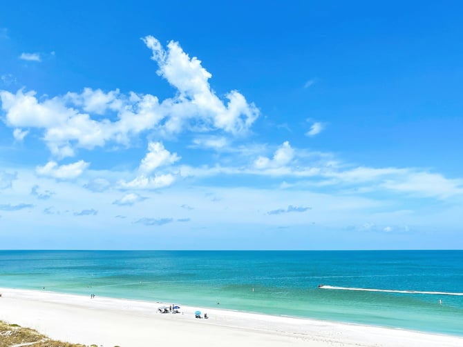 Wide white sand beach with turquoise water under a bright blue sky