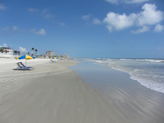 Wide sandy Daytona Beach with beach chairs, umbrellas and hotels along the shore