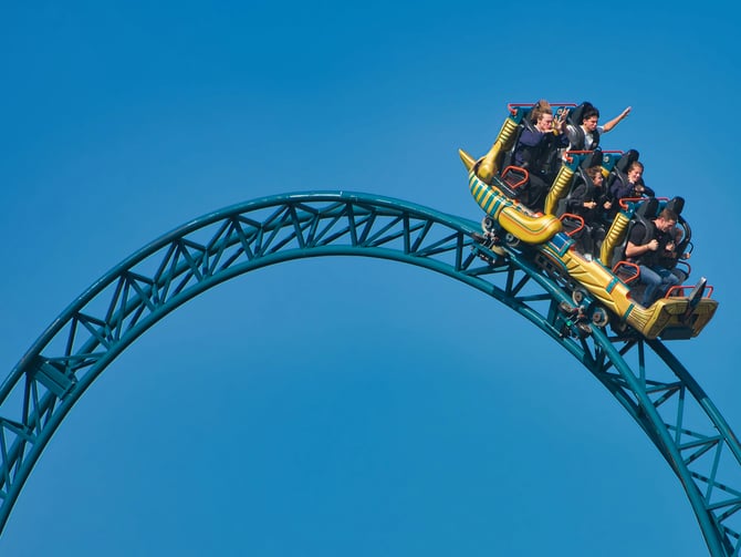 Roller coaster cresting a loop against a clear blue sky
