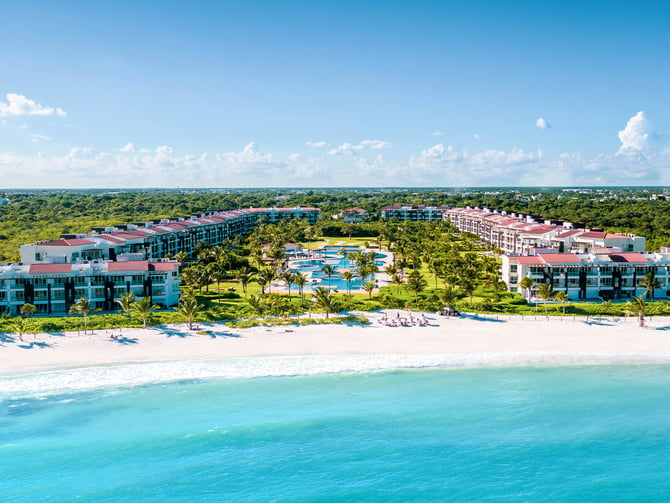 Aerial view of a beachfront resort pool with palm trees and turquoise Caribbean sea, Playa del Carmen, Mexico